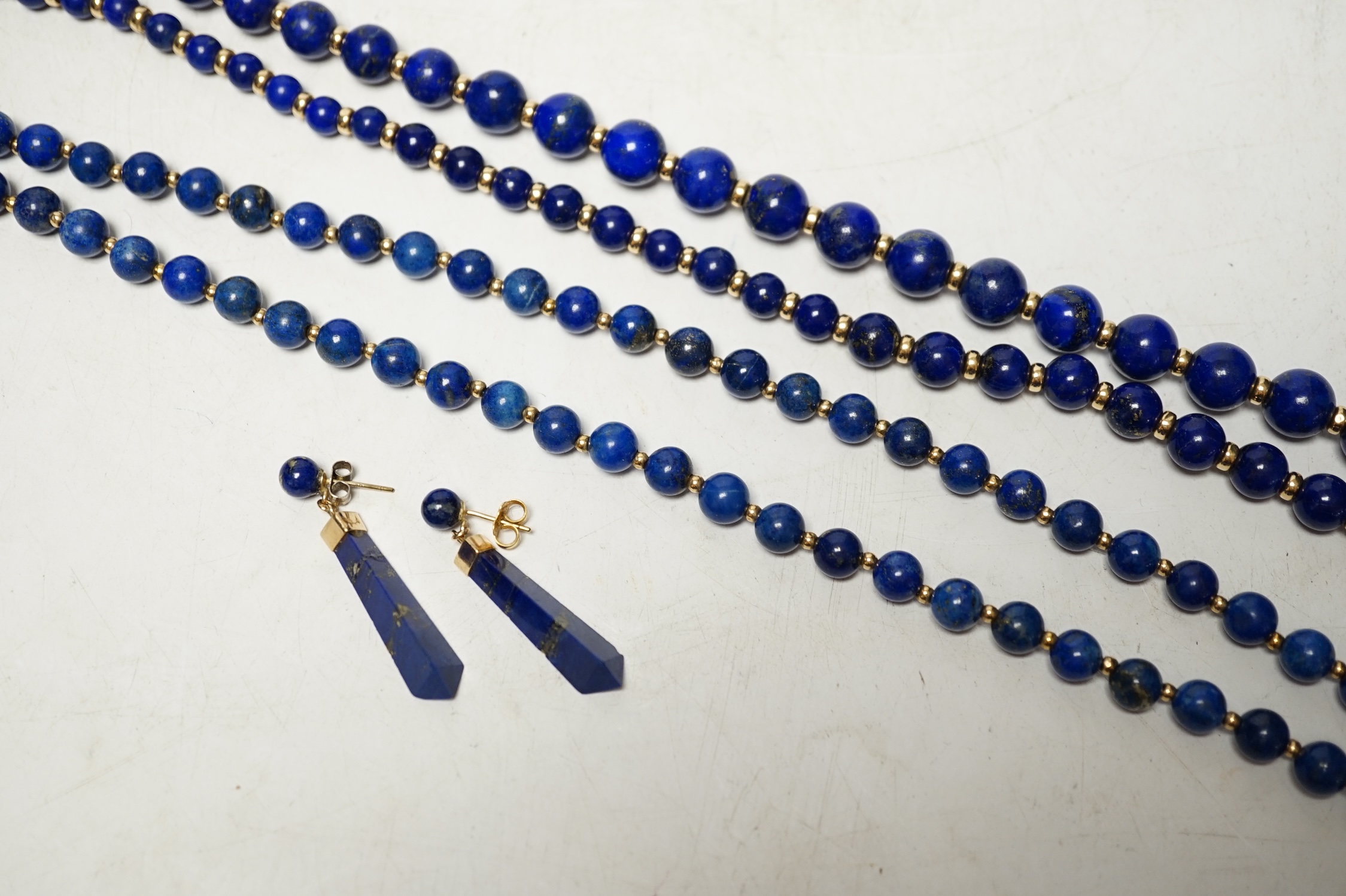 Two lapis lazuli bead necklaces with yellow metal spacers, largest 76cm and a pair of earrings. Condition - fair